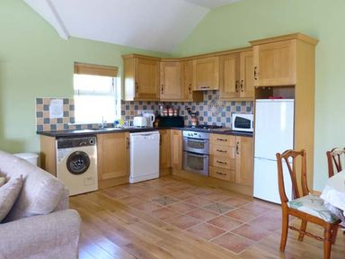 A kitchen with wooden cabinets appliances and dining chairs at The Bay in Caherdaniel County Kerry