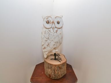 A carved wooden owl sculpture on a wooden stump on a wooden table against a white wall at Mary Kates Cottage in Narin County Donegal