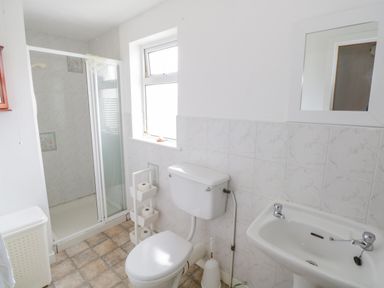 A bathroom with a shower enclosure toilet sink mirror and window at Mary Kates Cottage in Narin County Donegal