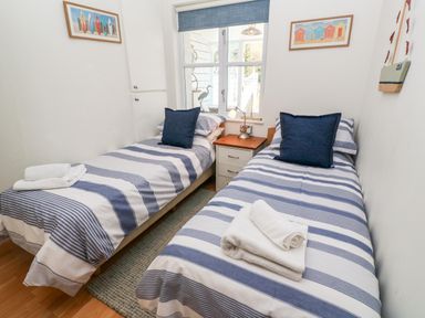 A bedroom with two single beds with striped bedding and a nightstand between at Waterside Cottage in Little Petherick Creek near Padstow