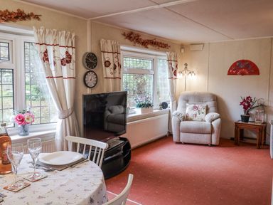 A living room with a sofa, dining table, and television at The Lodge in Old Buckenham near Attleborough