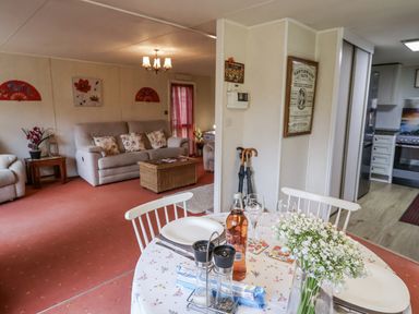 A living room with a sofa and dining area at The Lodge in Old Buckenham near Attleborough