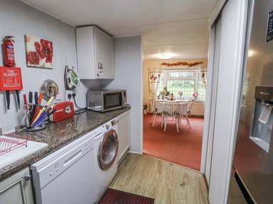 A kitchen with appliances and access to a dining area at The Lodge in Old Buckenham near Attleborough