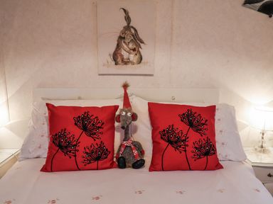 A bed with red pillows and a stuffed animal in a bedroom at The Lodge in Old Buckenham near Attleborough