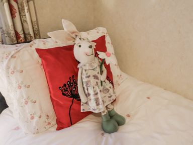 A rabbit doll on a bed with decorative pillows at The Lodge Old Buckenham near Attleborough