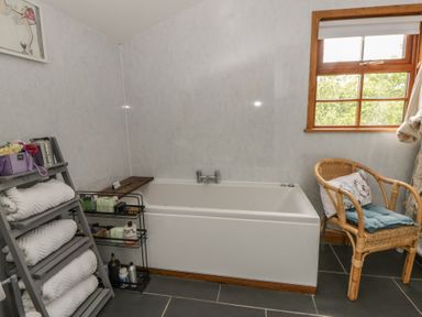 A bathroom with a bath tub and a towel rack at Yr Hen Llaethdy Blaen-Cil-Llech near Newcastle Emlyn