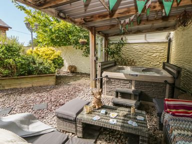 A garden area with a hot tub and outdoor seating at Yr Hen Llaethdy in Blaen-Cil-Llech near Newcastle Emlyn