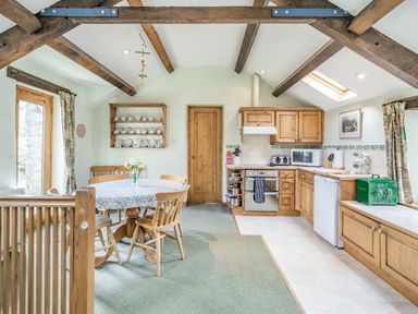 A kitchen with wooden cabinets and a round dining table with chairs at Moresdale Bank Cottage Lambrigg near Sedbergh and Kendal