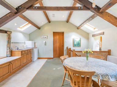 A kitchen and dining area with wooden beams a round table and chairs and a kitchenette at Moresdale Bank Cottage Lambrigg near Sedbergh and Kendal