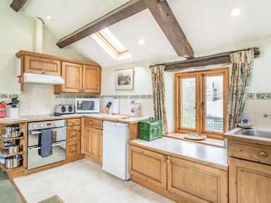 A kitchen with wooden cabinets a skylight window and a green bread box at Moresdale Bank Cottage in Lambrigg near Sedbergh and Kendal