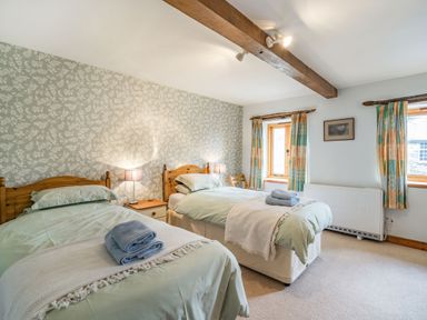 A bedroom with two single beds side by side with folded towels on each bed at Moresdale Bank Cottage in Lambrigg near Sedbergh and Kendal