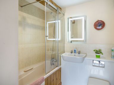 A bathroom with a bathtub shower combo a sink with a soap dispenser and a mirror above at Moresdale Bank Cottage Lambrigg near Sedbergh and Kendal