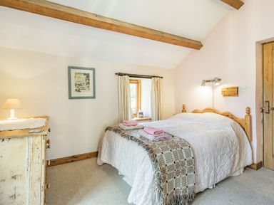 A bedroom with a bed and towels on it a window with curtains a wooden dresser and a lamp at Moresdale Bank Cottage Lambrigg near Sedbergh and Kendal