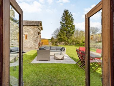 A garden with outdoor seating including a sofa set and a dining table with chairs at Moresdale Bank Cottage in Lambrigg near Sedbergh and Kendal
