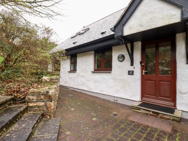 Exterior view of a white house with brown door and windows and stone steps in front at Lodge 22 Cherry in Wadebridge