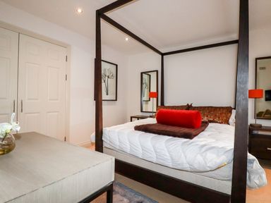 A bedroom with a four-poster bed with pillows and a blanket at Lodge 22 Cherry in Wadebridge