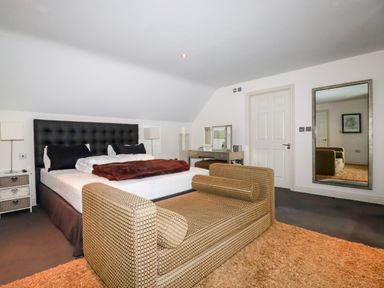 A bedroom with a bed a sofa a dressing table and a large mirror at Lodge 22 Cherry in Wadebridge