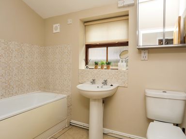 A bathroom with a bathtub sink toilet and a mirrored cabinet at Penrallt Cottage in Y Felinheli near Caernarfon