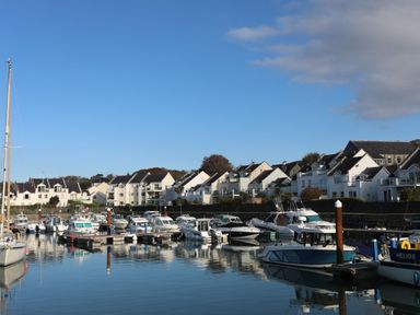 A marina with boats docked and white houses in the background at Penrallt Cottage in Y Felinheli near Caernarfon