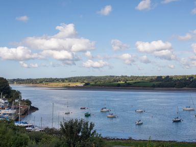 A river with sailboats anchored and green hills in the background at Penrallt Cottage in Y Felinheli near Caernarfon