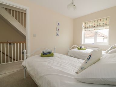A bedroom with two single beds white bedding and rolled towels near a window at Sandlings Hollesley near Woodbridge