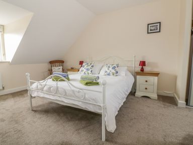 A bedroom with a white metal bed frame bedside tables and a wooden chair at Sandlings Hollesley near Woodbridge
