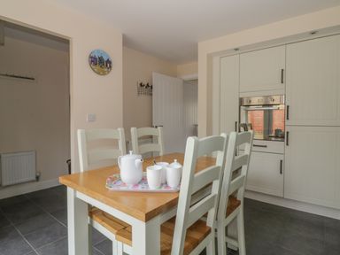 A dining area with a wooden table and four chairs and a built-in oven in a kitchen at Sandlings in Hollesley near Woodbridge