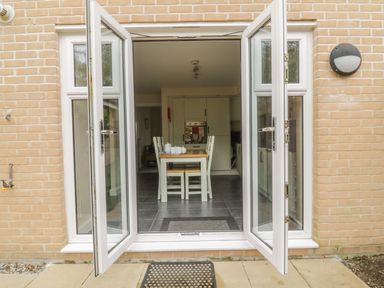 A dining area with a table and four chairs viewed through open double doors at Sandlings in Hollesley near Woodbridge