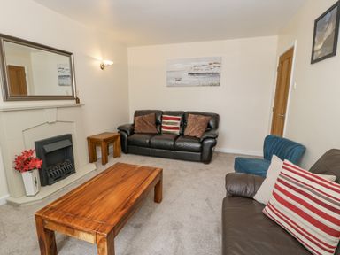 A living room with leather sofas wooden tables and a fireplace at Gwelfor in Morfa Bychan
