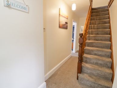 A hallway with carpeted stairs and a welcome sign at Gwelfor in Morfa Bychan