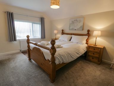 A bedroom with a wooden bed and two bedside tables with lamps at Gwelfor in Morfa Bychan