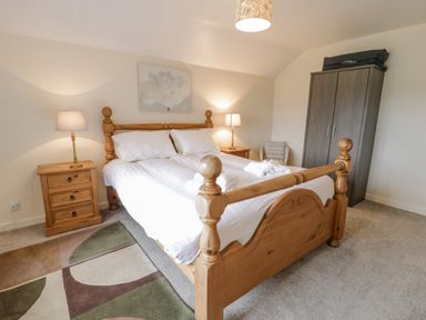 A bedroom with a wooden bed and two bedside tables with lamps at Gwelfor in Morfa Bychan