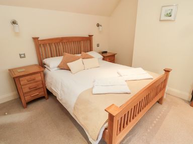 A bedroom with a wooden double bed with pillows and folded towels and two wooden bedside tables at The Granary in Longframlington near Alnwick