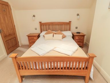 A bedroom with a wooden bed frame two bedside tables with lamps and towels on the bed at The Granary in Longframlington near Alnwick