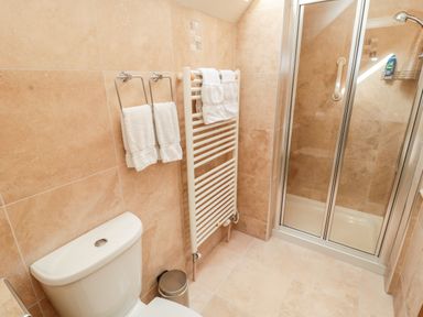 A bathroom with a toilet a towel rack with towels and a glass shower enclosure at The Granary Longframlington near Alnwick