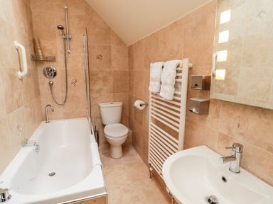 A bathroom with a bathtub shower toilet sink towel rack and mirror at The Granary in Longframlington near Alnwick