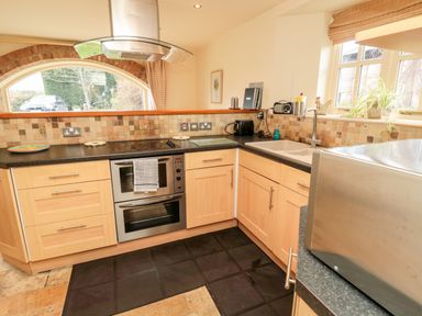 A kitchen with wooden cabinets a stainless steel oven stovetop and microwave at The Granary in Longframlington near Alnwick