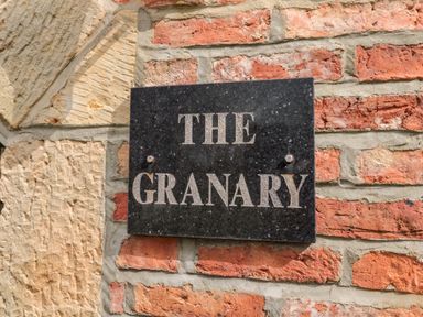 A black stone plaque with the words The Granary on a brick and stone wall at The Granary in Longframlington near Alnwick