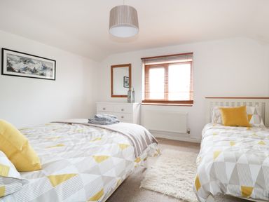 A bedroom with two beds a dresser a mirror a window with blinds and a mountain picture on the wall at Lynton House in Ruardean Hill near Drybrook