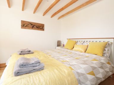 A bedroom with a bed with yellow and grey bedding and folded towels on the bed at Lynton House in Ruardean Hill near Drybrook