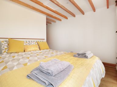 A bedroom with a bed with yellow and gray bedding and towels on top at Lynton House Ruardean Hill near Drybrook