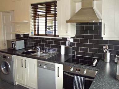 A kitchen with a washing machine dishwasher oven sink microwave and utensils at Hartam House in Falstone near Kielder and Bellingham