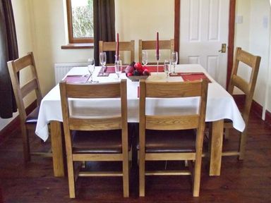 A dining room with a rectangular table set with six wooden chairs at Hartam House in Falstone near Kielder and Bellingham