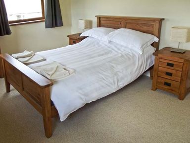 A bedroom with a wooden bed and two bedside tables with lamps at Hartam House in Falstone near Kielder and Bellingham