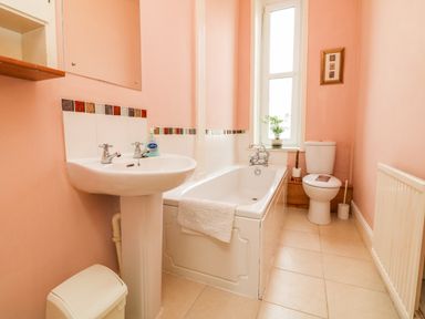 A bathroom with a sink a bathtub a toilet a window and a radiator at Penryn in Ilfracombe