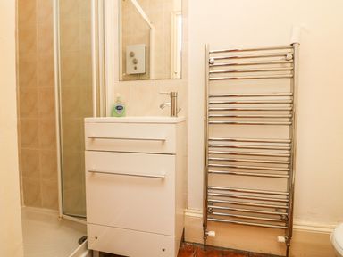 A bathroom with a sink cabinet shower enclosure and heated towel rail at Penryn in Ilfracombe