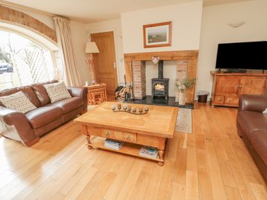 A living room with leather sofas a wooden coffee table a fireplace and a television at The Red Barn in Longframlington near Alnwick
