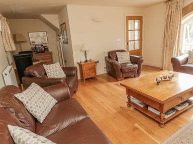 A living room with leather sofas a wooden coffee table and a side table at The Red Barn in Longframlington near Alnwick