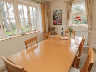 A dining room with wooden table and chairs flowers and a bottle on the table at The Red Barn Longframlington near Alnwick