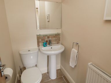 A bathroom with a toilet, sink, mirror, hand towel, radiator, and soap dispenser at The Red Barn in Longframlington near Alnwick